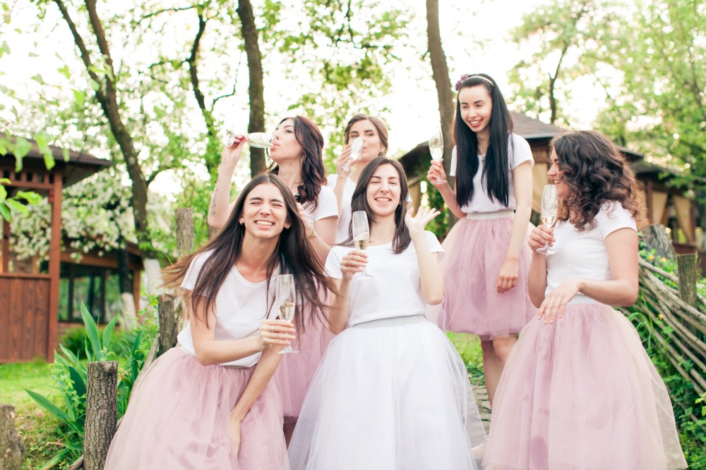 Damas de honor con faldas rosas bebiendo champán en un evento
