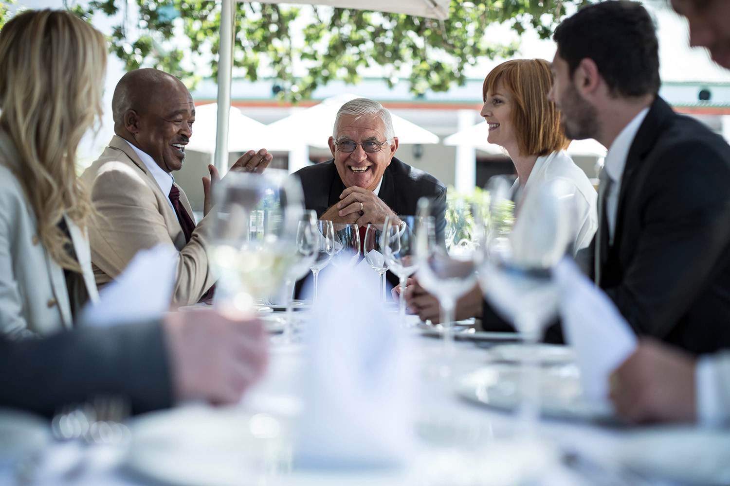 Anciano presidiendo una mesa de empresarios, contento de que le hagan una despedida por su jubilación en un evento corporativo